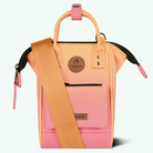 A small structured handbag in pastel pink and peach-orange with a wide orange shoulder strap, black zipper trim, and a round brown logo patch reading CABAIA on the front, shown on a clean white background.