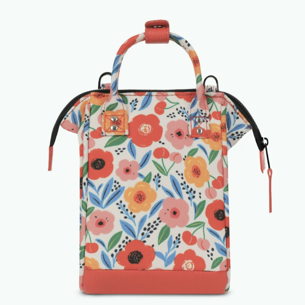 A structured tote bag with a vibrant floral print on a cream background, featuring coral orange handles, a matching bottom base, and black zipper pulls.
