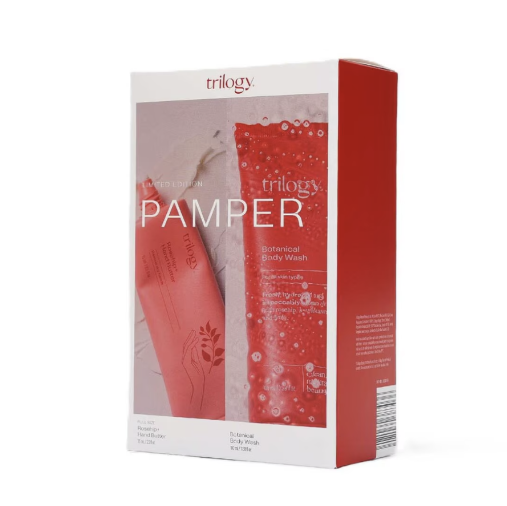 A boxed body wash set from Trilogy, featuring a white and red package with a front window showing the product tube and bottle, photographed on a clean white background.
