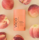 Vico natural deodorant stick surrounded by peaches on a beige background