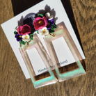 Pair of earrings with floral design on a card with 'Handmade in Ireland' text, placed on a wooden surface.