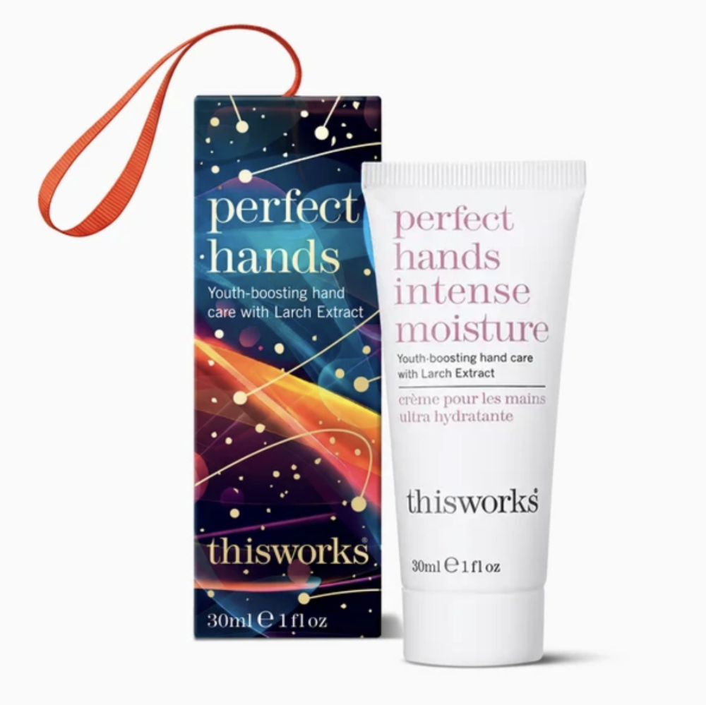 Thisworks Perfect Hands Intense Moisture youth-boosting hand care set, featuring a white squeeze tube and a dark blue starry-patterned box with an orange wrist strap, on a white background.