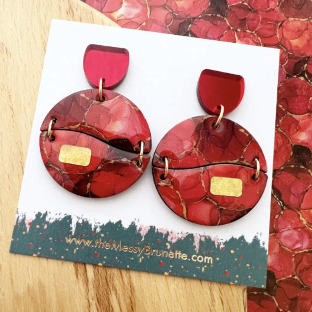 Red marbled earrings on a branded card with a colorful background