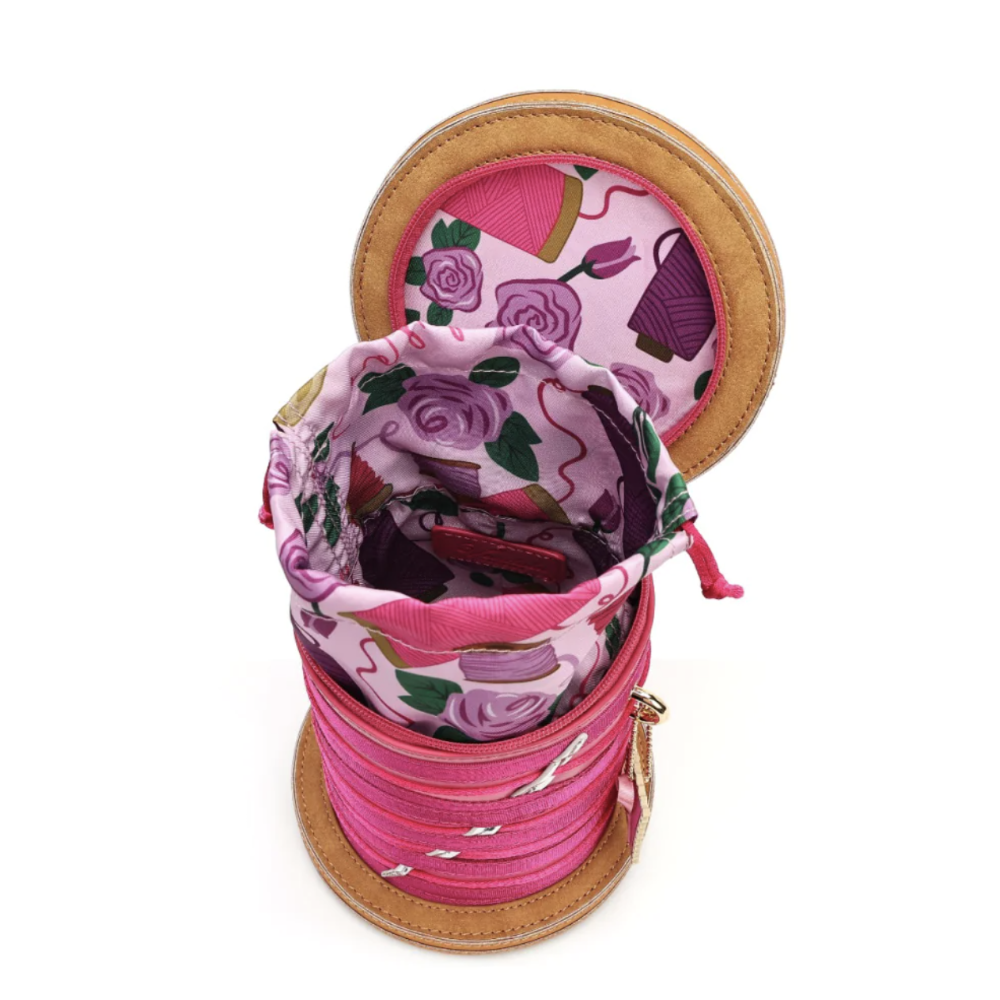 A round zippered bag with a tan leather-like trim, shown open to reveal a pink and purple floral-patterned interior lining and multiple pink zipper compartments stacked inside.