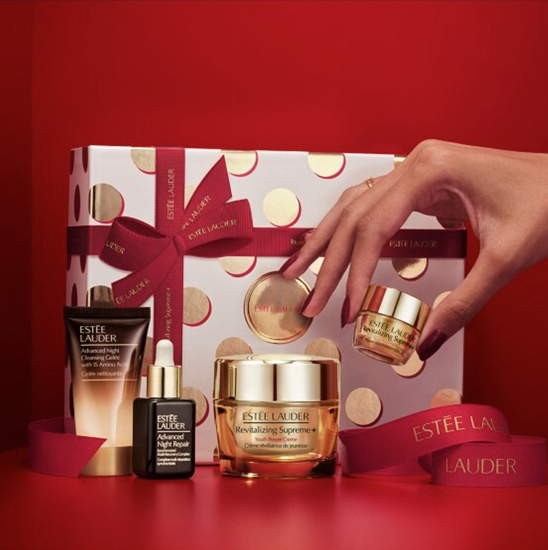 Estée Lauder skincare products with a hand interacting on a red background