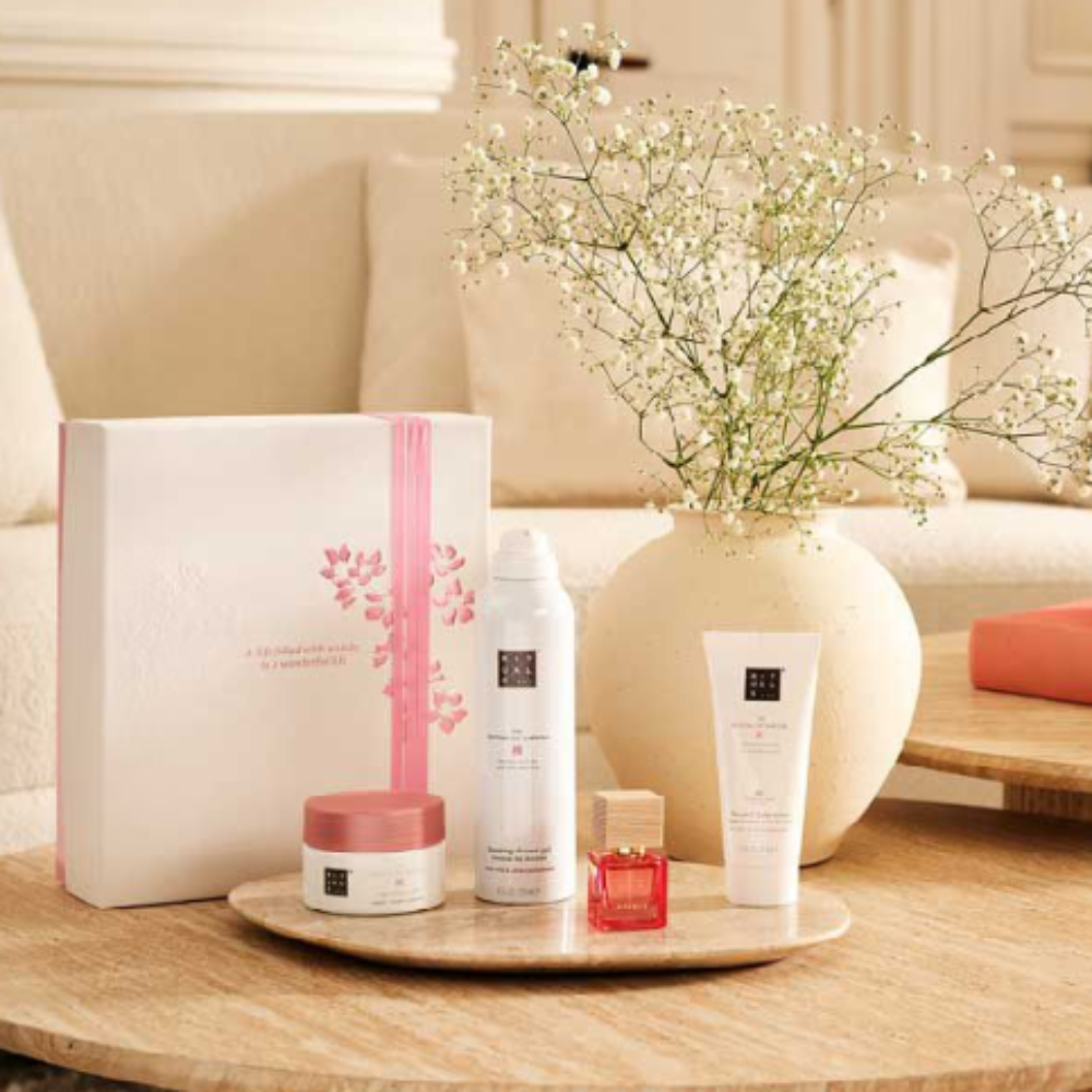 Cosmetic products on a wooden tray with a vase of flowers in the background