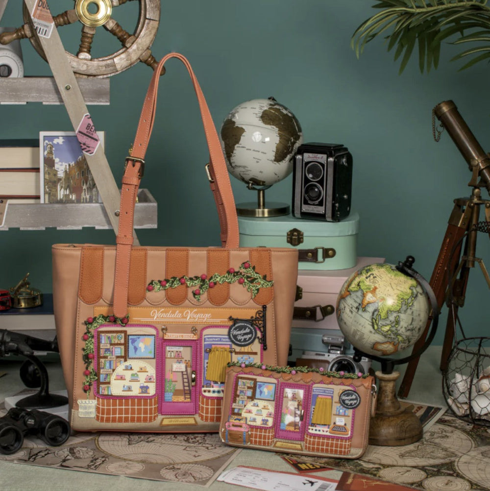 Tote bag with detailed design on a surface with globes and cameras in the background