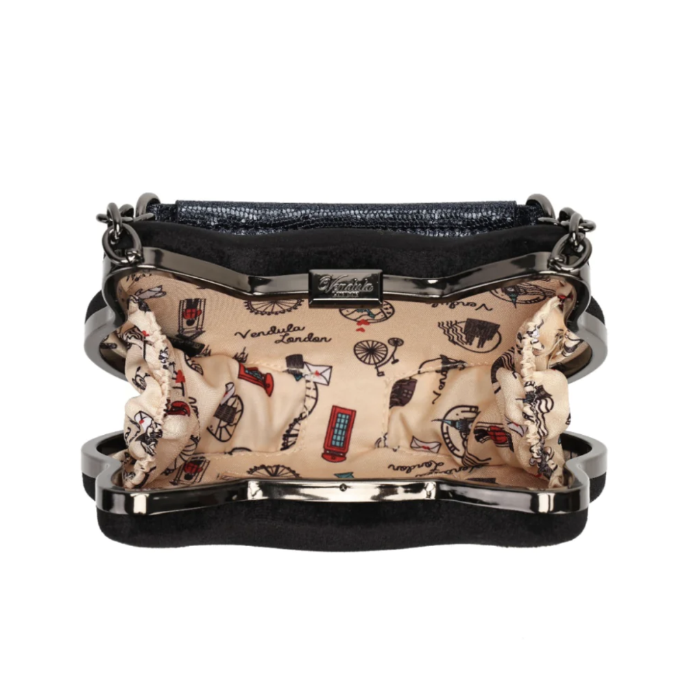 A black velvet clutch purse with a glossy black metal frame and a beige patterned lining featuring London-themed illustrations like red telephone booths, black cats, and the words 'London'.