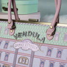 Handbag with 'Vendula' and 'Grand Vendula Hotel' design on a light green background