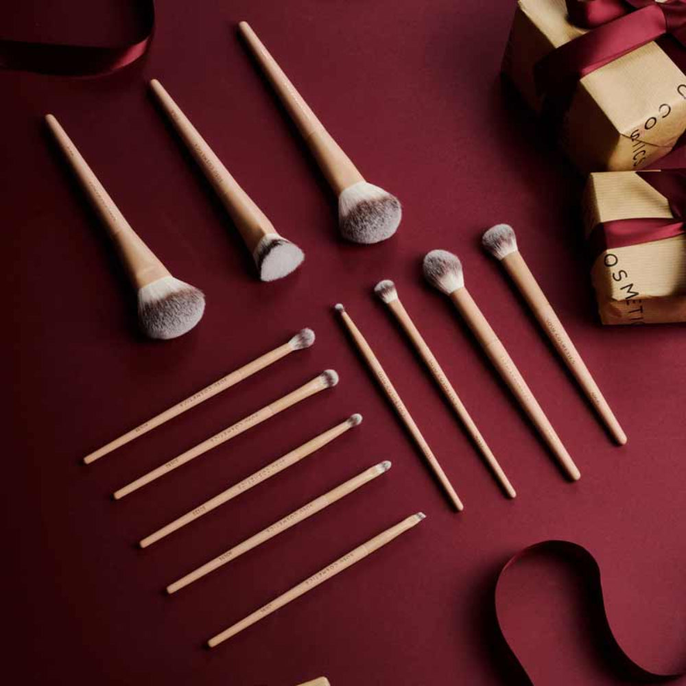 Makeup brushes on a dark red surface with a gift box in the background