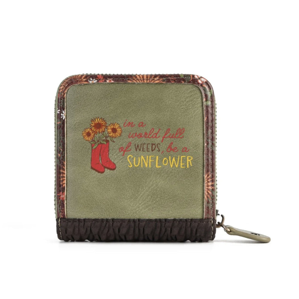 A small zip-around wallet with a distressed olive green front, featuring a printed design of red rain boots and sunflowers with the text 'in a world full of weeds, be a SUNFLOWER'. The wallet has a floral patterned border and a dark brown textured bottom trim, shown on a white background with a metal keychain ring attached.