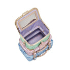 Stack of pastel-colored suitcase style bags with a mirror on a white background
