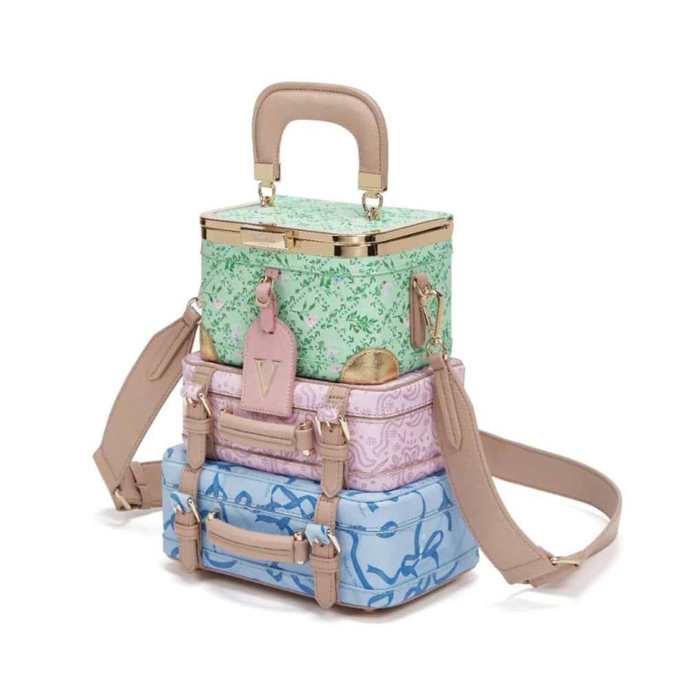 Stack of pastel-colored suitcases with floral patterns on a white background