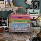 Stack of books with a decorative box on top, surrounded by travel-themed items.