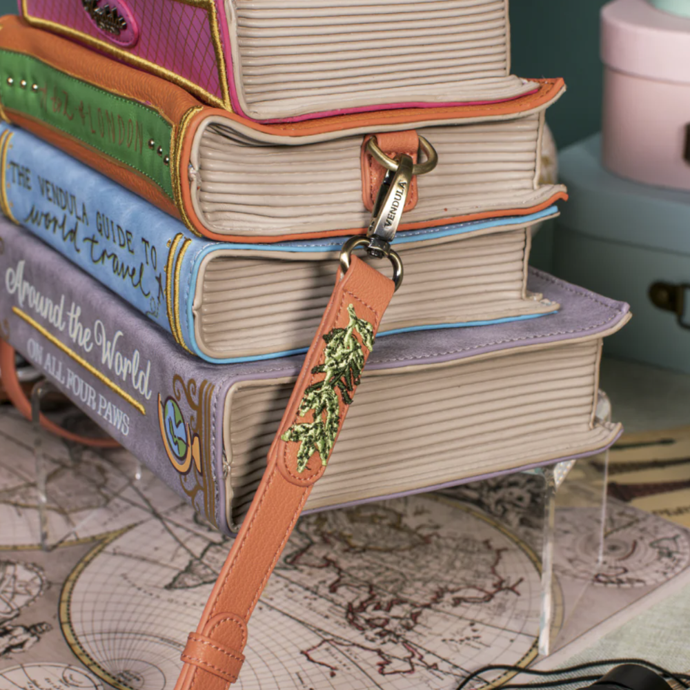 Stack of books with a handbag strap on top, set against a map background