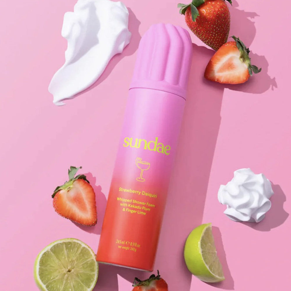 Sundae strawberry lime flavor whipped shower foam with strawberries and whipped cream on a pink background