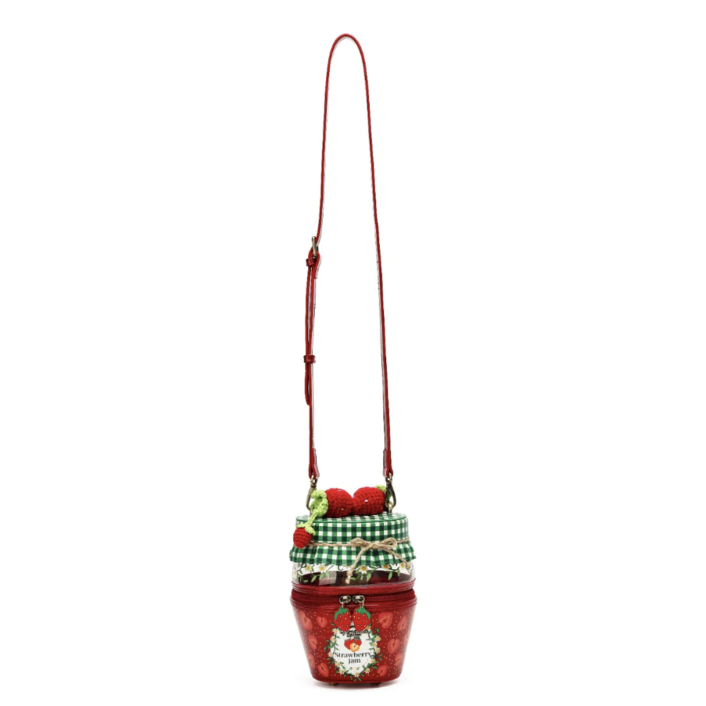 A red crossbody bag designed to look like a strawberry jam jar, featuring a green and white gingham checkered fabric liner, red strawberries, and a red strap on a plain white background.