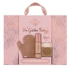 Bellamianta The Golden Trilogy Dark tan set in a pink gift bag with a handle. The set includes a beige mitt, a rose gold-toned tan bottle, and a compact powder, all displayed against a white background.