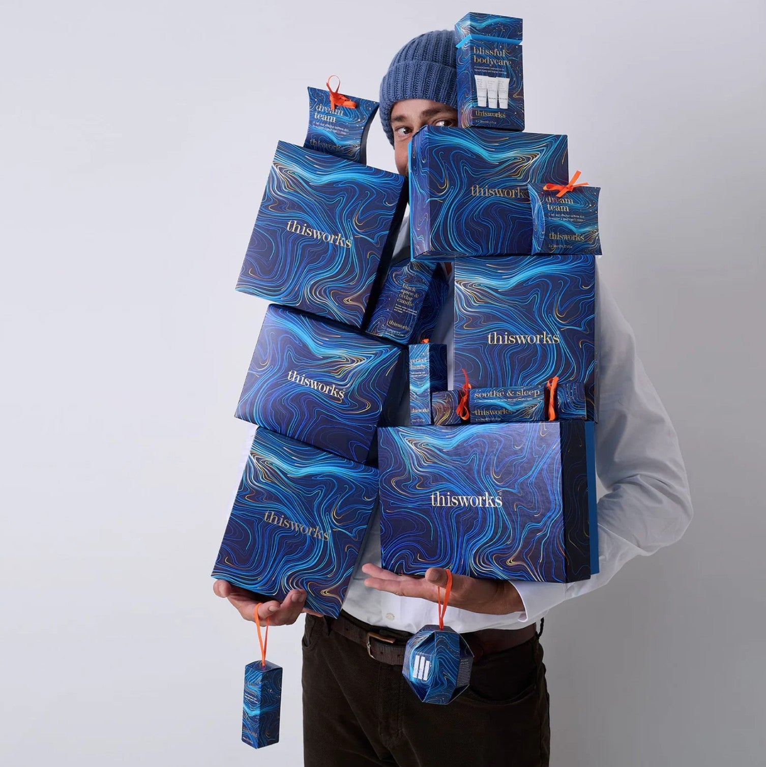 Person holding multiple blue 'thisworks' boxes against a white background