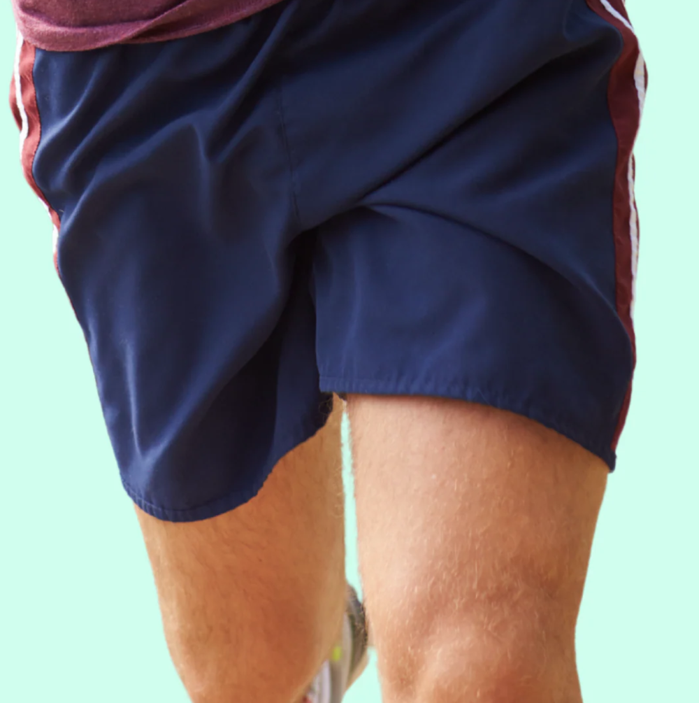 Navy athletic shorts with red accents on a light green background