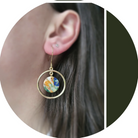 Close-up of an earring with a colorful stone worn by a person.