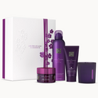 A 4-piece skincare set by Rituals in a white and purple gift box, featuring a purple pump bottle, a purple tube, a purple jar, and a purple candle on a white background.