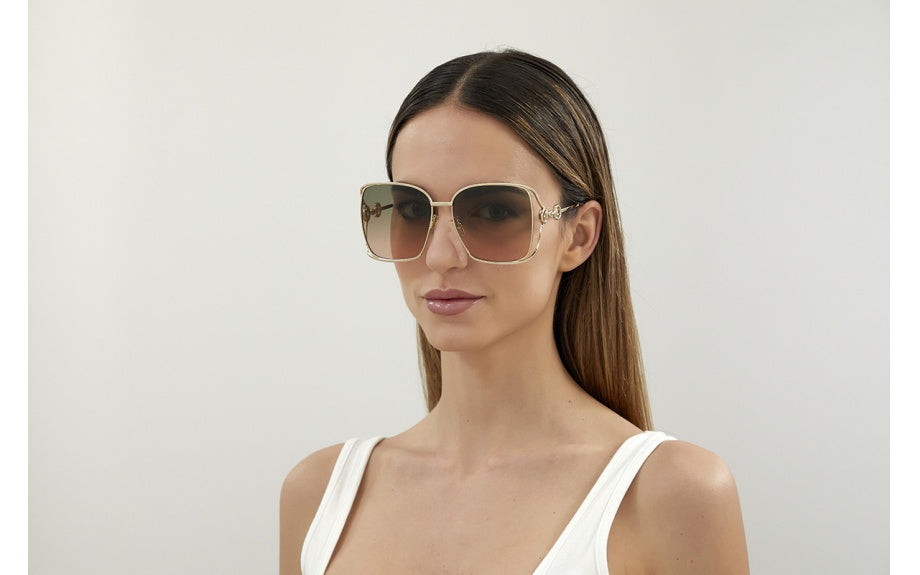 Girl wearing Gucci big gold square sunglasses